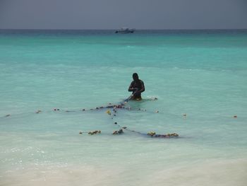 People on boat in sea against clear sky