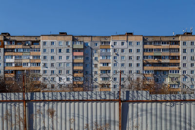 Buildings by river against clear sky during winter