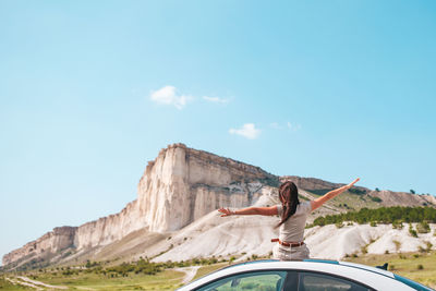 Woman with arms raised against sky