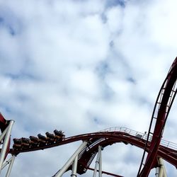 Low angle view of ferris wheel against cloudy sky