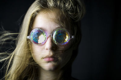 Woman with kaleidoscope glasses against black background