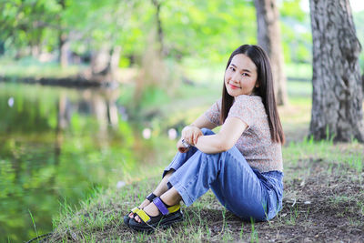 Portrait of smiling young woman sitting on land