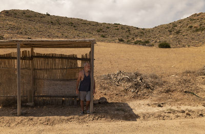 Portrait of adult man waiting bus in a wooden bus stand in nature park in summer