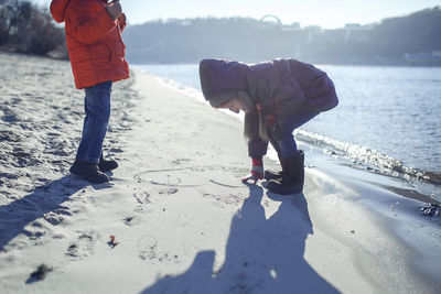 Full length of girl making heart shape on sand at beach