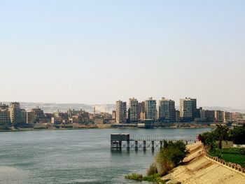 River by buildings against clear sky