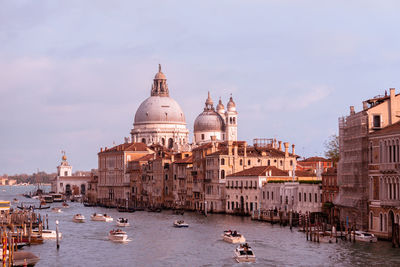 Boats in canal amidst buildings against sky