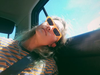 Low angle view of young woman wearing sunglasses sitting in car