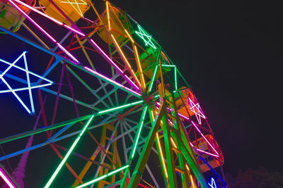 Low angle view of illuminated ferris wheel against sky at night