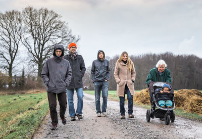 Family walking on road against sky during winter