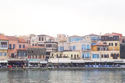 Residential buildings by river against clear sky