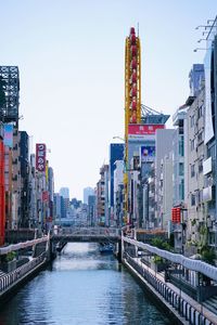 Bridge over river by buildings against clear sky