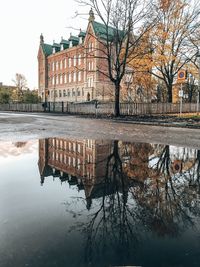 Reflection of building in lake against sky in city