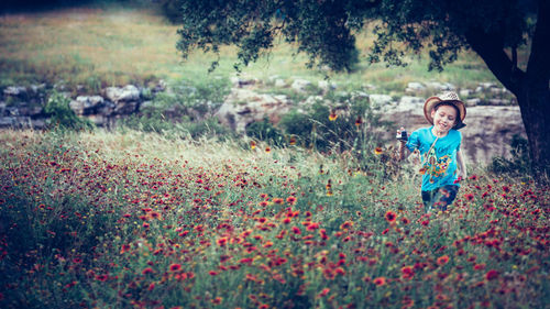 Smiling girl standing amidst flowers in field