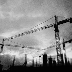 Low angle view of crane against cloudy sky