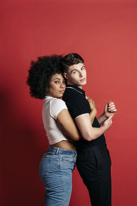 Stylish diverse girlfriend and boyfriend posing in a studio shooting with red background