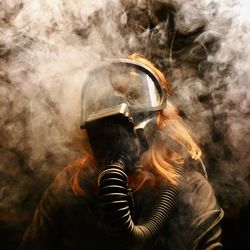 Close-up of woman wearing gas mask in darkroom