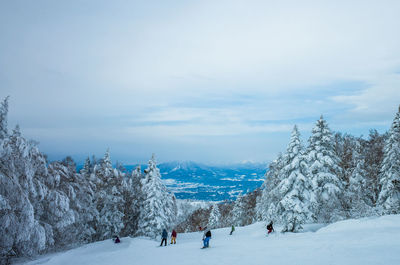 People on snow covered landscape against sky