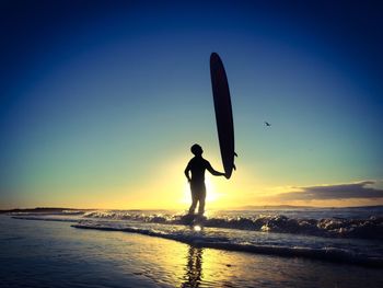 Silhouette of people on beach at sunset