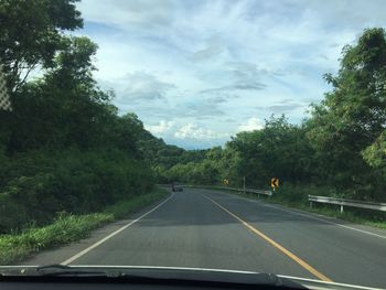 Road amidst trees seen through car windshield