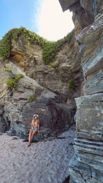 Young woman standing by rock formation