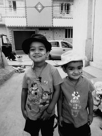 Portrait of smiling brother and sister standing amidst building