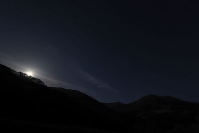 Low angle view of silhouette mountain against sky at night