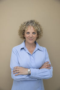 Businesswoman with arms crossed against brown background