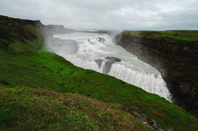 Scenic view of waterfall against sky