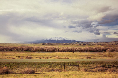 Scenic view of field and mountains against cloudy sky