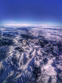 Aerial view of sea and landscape against blue sky