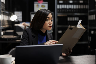 Young woman using laptop while sitting on table