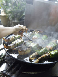 Cropped hand making fish on cooking pan