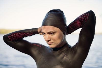 Thoughtful female swimmer wearing swimming cap at lakeshore