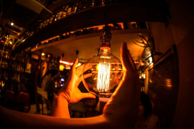 Close-up of man holding glass of illuminated candles