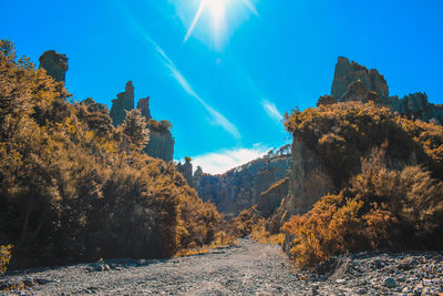 Scenic view of dirt road amidst rock formation against sky