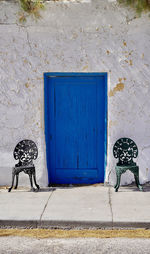 2 chairs left and right of a blue door against a white wall 