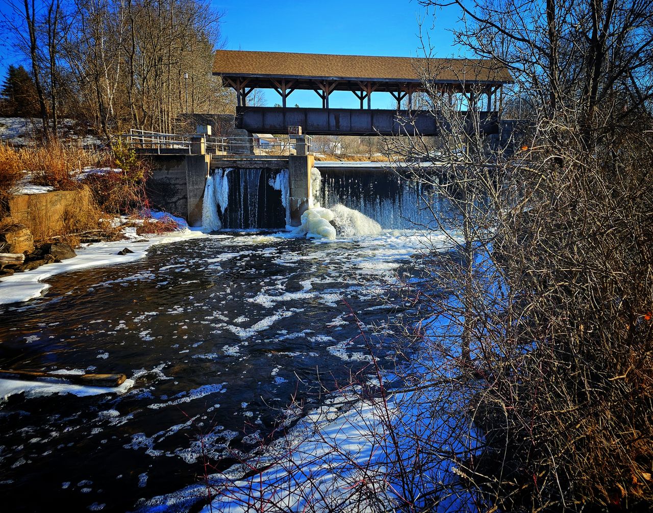 winter, tree, water, architecture, built structure, nature, reflection, plant, river, snow, bare tree, cold temperature, waterfall, sky, no people, day, bridge, building exterior, flowing water, autumn, ice, blue, frozen, environment, outdoors, scenics - nature, clear sky, beauty in nature, motion, flowing