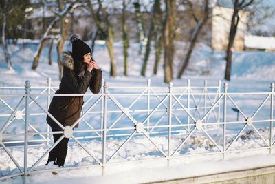 Woman leaning on railing during winter