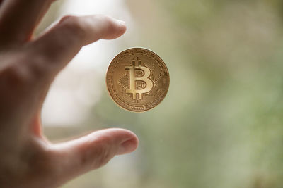 Close-up of hand holding coin against blurred background