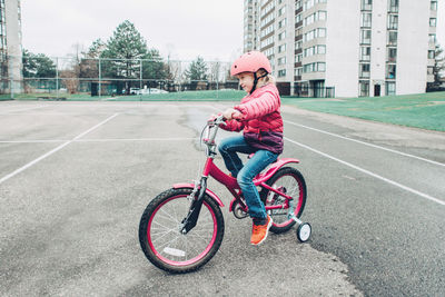 Full length of girl riding bicycle on walkway in city