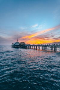 Pier over sea against sky during sunset