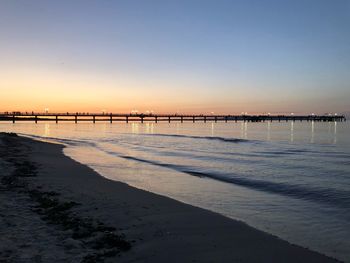 Scenic view of beach against clear sky during sunset