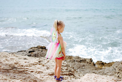 Portrait of little girl in butterfly costume standing at beach