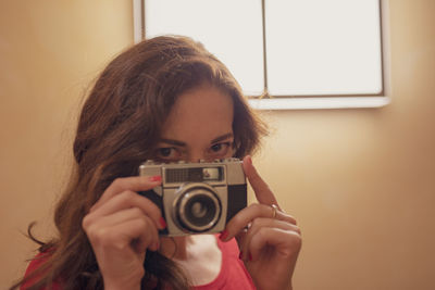 Portrait of woman photographing camera at home