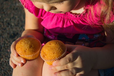 Midsection of girl holding muffins while sitting at yard