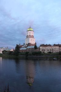 Church in front of river against cloudy sky