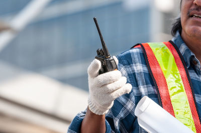 Close-up of man holding camera while standing at construction site