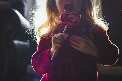 Midsection of girl eating lollipop at home