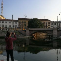 Reflection of buildings in canal against clear sky