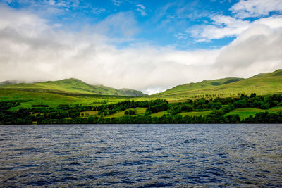 Scenic view of river by mountains against sky